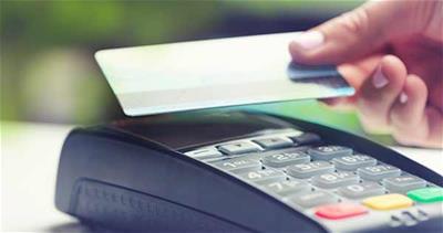 hand holds credit card over terminal for tap to pay